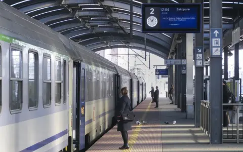Pociąg na peronie, tablica informacyjna z trasą do Zakopanego, pasażerowie.