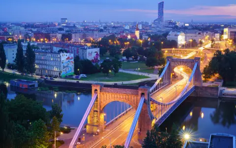Most Wrocławia w niebieskiej godzinie. Most Grunwaldzki i ruch uliczny tworzą świetlne smugi na tle miasta.