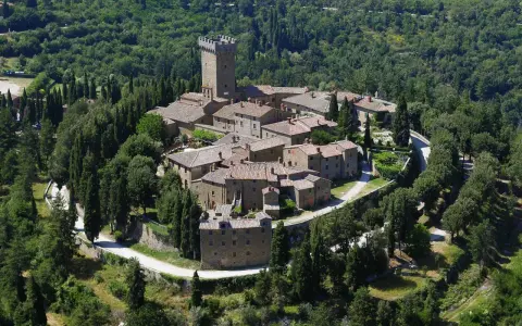 Il castello di Gargonza, un borgo medievale in pietra con torre, immerso nel verde della Toscana.