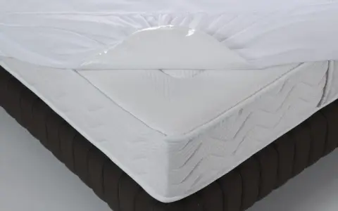 Un matelas blanc avec une alèse imperméable soulevée, montrant de quel côté mettre une alèse pour protéger le matelas.
