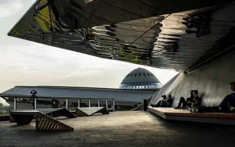 Nowoczesna architektura i ludzie odpoczywający pod zadaszeniem. W tle kopuła Muzeum Śląskiego, jedna z głównych katowice atrakcje.