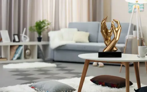 Esculturas de manos doradas, arte moderno que adorna un salón acogedor con sofá gris y alfombras mullidas.