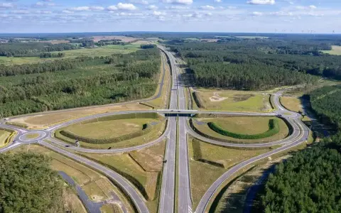 Węzeł drogowy na trasie Poznań-Kołobrzeg. Nowoczesna infrastruktura drogowa otoczona lasami i polami.