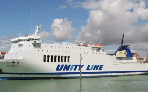 Biały prom Galileusz z napisem "UNITY LINE" cumuje w porcie.