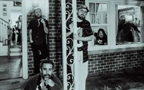 Band of Horses i Stockholm. Fyra män poserar utanför ett hus, en tittar ut genom ett fönster.