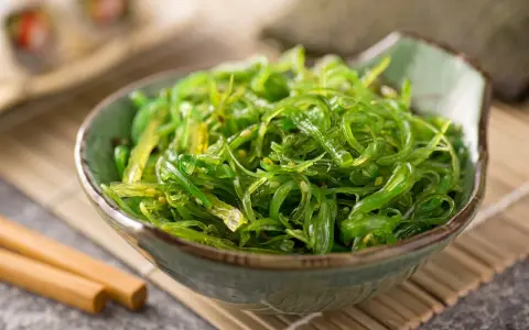 Miseczka zielonej sałatki z wodorostów wakame, idealna do sushi. Prosty wakame przepis na zdrową przekąskę.