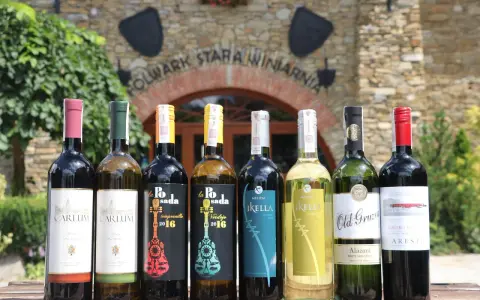 Wybierasz jakie wino na wesele? Rząd butelek z winem czerwonym i białym przed starą winnicą.