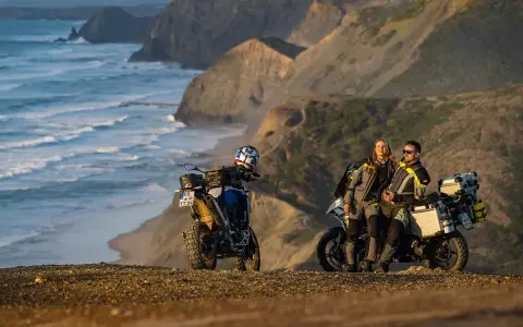 Para motocyklistów odpoczywa na klifie, podziwiając dzikie wybrzeże Algarve. Ich motocykle gotowe do dalszej podróży.