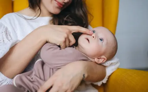Mama delikatnie dotyka noska dziecka, które ma katar przy ząbkowaniu.