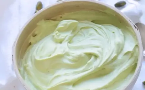 Un bol rempli de ganache pistache onctueuse, parsemé de pistaches entières. Une gourmandise verte et appétissante.