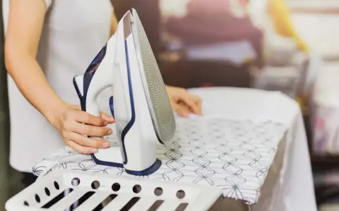 Persona plancha un vestido de satén con cuidado en una tabla de planchar.