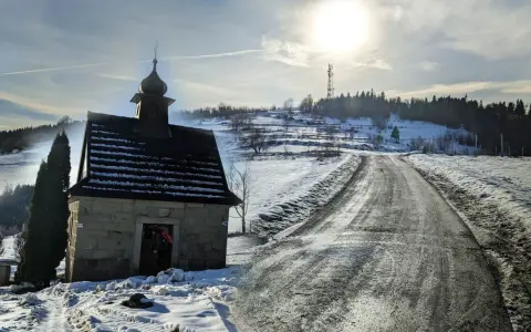 Kamienna kapliczka na zboczu Koskowej Góry, zimowa droga i słońce.