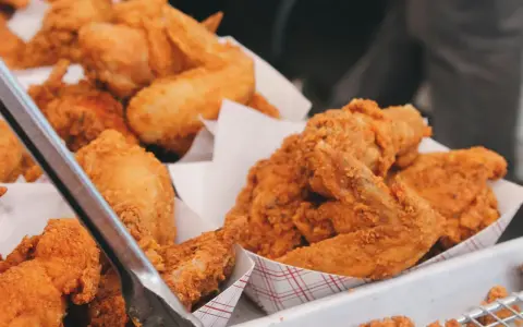 Un surtido de crujiente pollo frito en recipientes de cartón. Las piezas doradas y sabrosas invitan a disfrutar de este clásico.