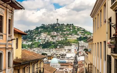 Widok na wzgórze z pomnikiem w Quito, stolicy Ekwadoru. Kolorowe budynki i wąskie uliczki tworzą malowniczy krajobraz.