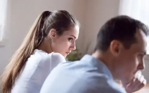 Una mujer mira con desconfianza a un hombre, reflejando el rencor en la pareja.