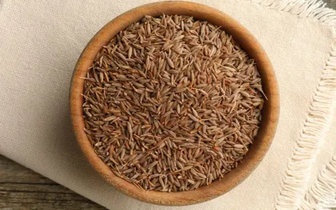 Drewniana miseczka pełna nasion kminu, znanego też jako kumin. Aromatyczna przyprawa gotowa do użycia.