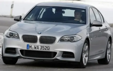Srebrne BMW z kierowcą za kierownicą, gotowe do liftingu auta na zimowej drodze.