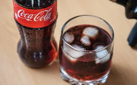 Szklanka z lodem i napojem, obok butelka Coca-Coli. Idealne na gorący dzień, gdy masz ochotę na wino z colą.