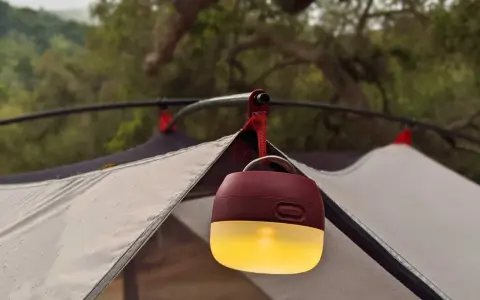 En mysig campingbelysning hänger från tältstången och lyser upp kvällen.