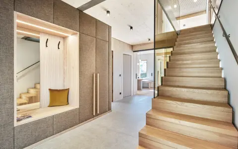 Moderne Diele mit Sitzbank und Garderobe, die Treppe aus verschiedenen **Hartholzarten** strahlt Wärme aus.