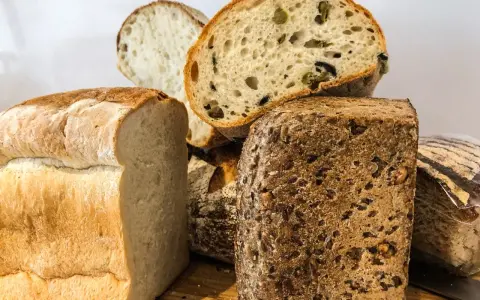 Różne rodzaje pieczywa, w tym bochenek z ziarnami, który może być odpowiedzią na pytanie: czy chleb razowy jest zdrowy?