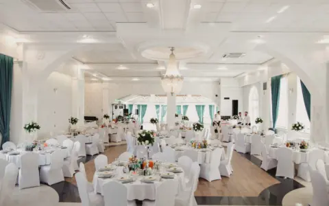 Elegancka sala weselna z białymi pokrowcami na krzesłach, sugerująca rezygnację z modeli tiffany na rzecz prostoty i klasy.