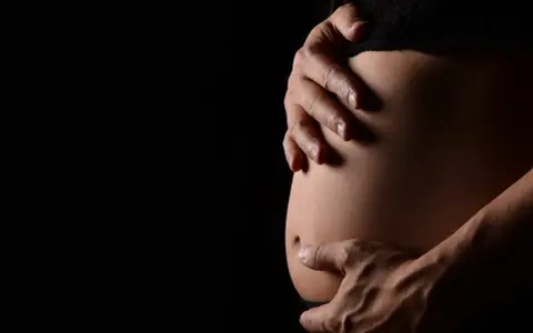 Mani che accarezzano un pancione. La ricerca sulle cause dell'autismo in gravidanza è complessa e in continua evoluzione.