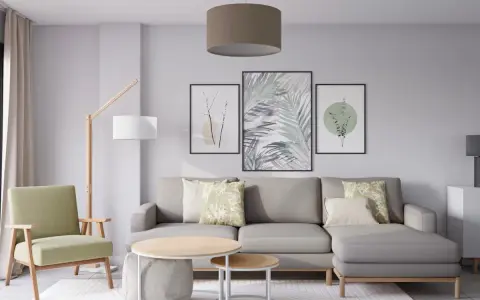 Salón moderno con sofá gris, sillón verde y tres cuadros con motivos botánicos, mostrando diferentes formas de poner cuadros en la pared.