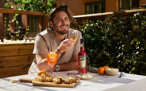 Man njuter av en Aperol Spritz och tilltugg på en solig uteservering.