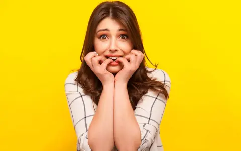 Ragazza con espressione preoccupata che si mangia le unghie, un chiaro segno di gestione dell'ansia.