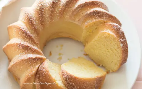 Una soffice torta di ricotta, spolverata di zucchero a velo, con una fetta tagliata.