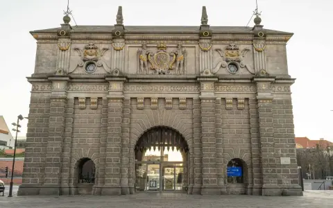 Majestatyczna Brama Wyżynna w Gdańsku, ozdobiona herbem i rzeźbami, zaprasza do zwiedzania.