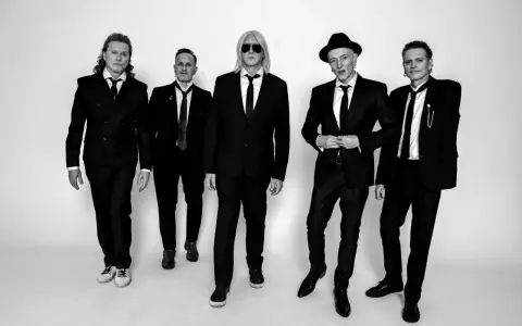 Fünf Männer in schwarzen Anzügen und Krawatten, die wie der titel von Def Leppard aussehen, posieren für ein Schwarz-Weiß-Foto.