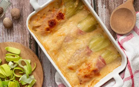 Gratin de poireaux au jambon, doré et crémeux, prêt à être dégusté. Une recette réconfortante.