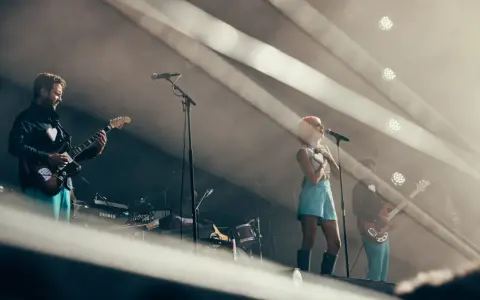 Un groupe de musique sur scène, avec une chanteuse aux cheveux roses et un guitariste. L'ambiance est électrique, typique d'un artiste funk.