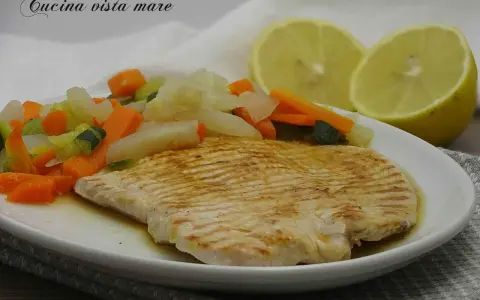 Fettine di tacchino appetitose, cotte alla griglia, servite con verdure miste e spicchi di limone.
