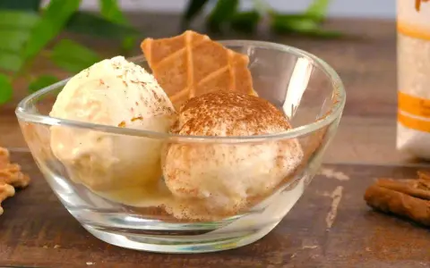 Dos bolas de helados caseros en un cuenco de cristal, espolvoreados con canela y acompañados de galletas.