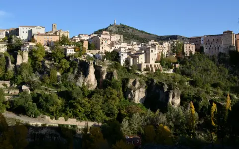 La ruta San Julián el Tranquilo en Cuenca: casas colgadas sobre riscos, vegetación frondosa y un cielo azul.