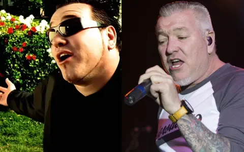 Steven Harwell w okularach przeciwsłonecznych śpiewa na tle ogrodu, obok Steven Harwell z tatuażami trzyma mikrofon na scenie.