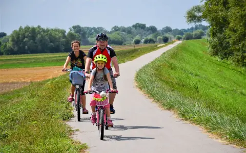 Rodzina na rowerach przemierza malownicze trasy rowerowe Małopolska. Słońce, zieleń i uśmiechy na twarzach.