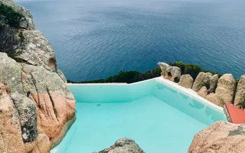 Piscina a sfioro incastonata tra rocce granitiche, con vista sul mare blu intenso. Un angolo di paradiso, forse un progetto di Alberto Ponis.