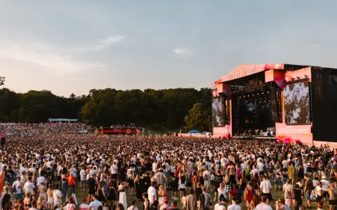 Tłum ludzi na festiwalu Bittersweet 2026, podziwiający scenę z wielkim ekranem i artystami. Słońce zachodzi, tworząc ciepłą atmosferę.