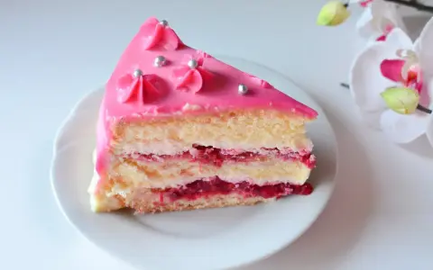 Pyszny tort malinowy z różowym lukrem i srebrnymi perełkami, przełożony kremem i malinową konfiturą.