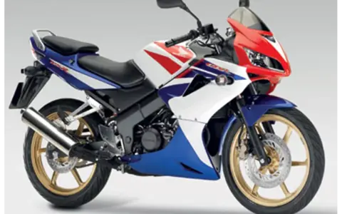Sportowy motocykl Honda CBR 125R w barwach V-Max, z czerwonym, białym i niebieskim malowaniem.