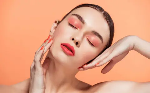 Maquillajes Euphoria: ojos con sombra coral brillante y labios rojos vibrantes, uñas a juego.