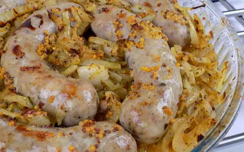 Biała kiełbasa surowa pieczona w piekarniku z cebulą i musztardą ziarnistą. Pyszne danie gotowe do podania.