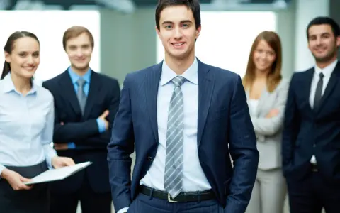 Equipo profesional sonriendo. Un ejemplo de como ir vestida a una entrevista de trabajo: traje oscuro, camisa clara y corbata.