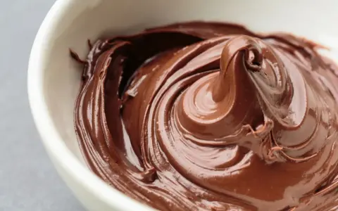 Cremige Schokoladencreme in einer weißen Schüssel. Ein Traum für alle, die Nutella selber machen gesund wollen.