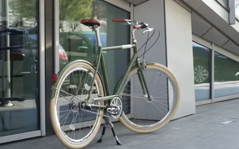 Stylowy, zielony rower do miasta z brązowym siodełkiem i uchwytami, gotowy na miejskie przygody.