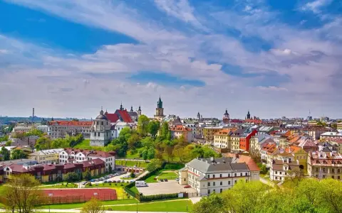 Widok na malownicze miasto w województwie lubelskim. Dachy kamienic, kościoły i zieleń pod błękitnym niebem.